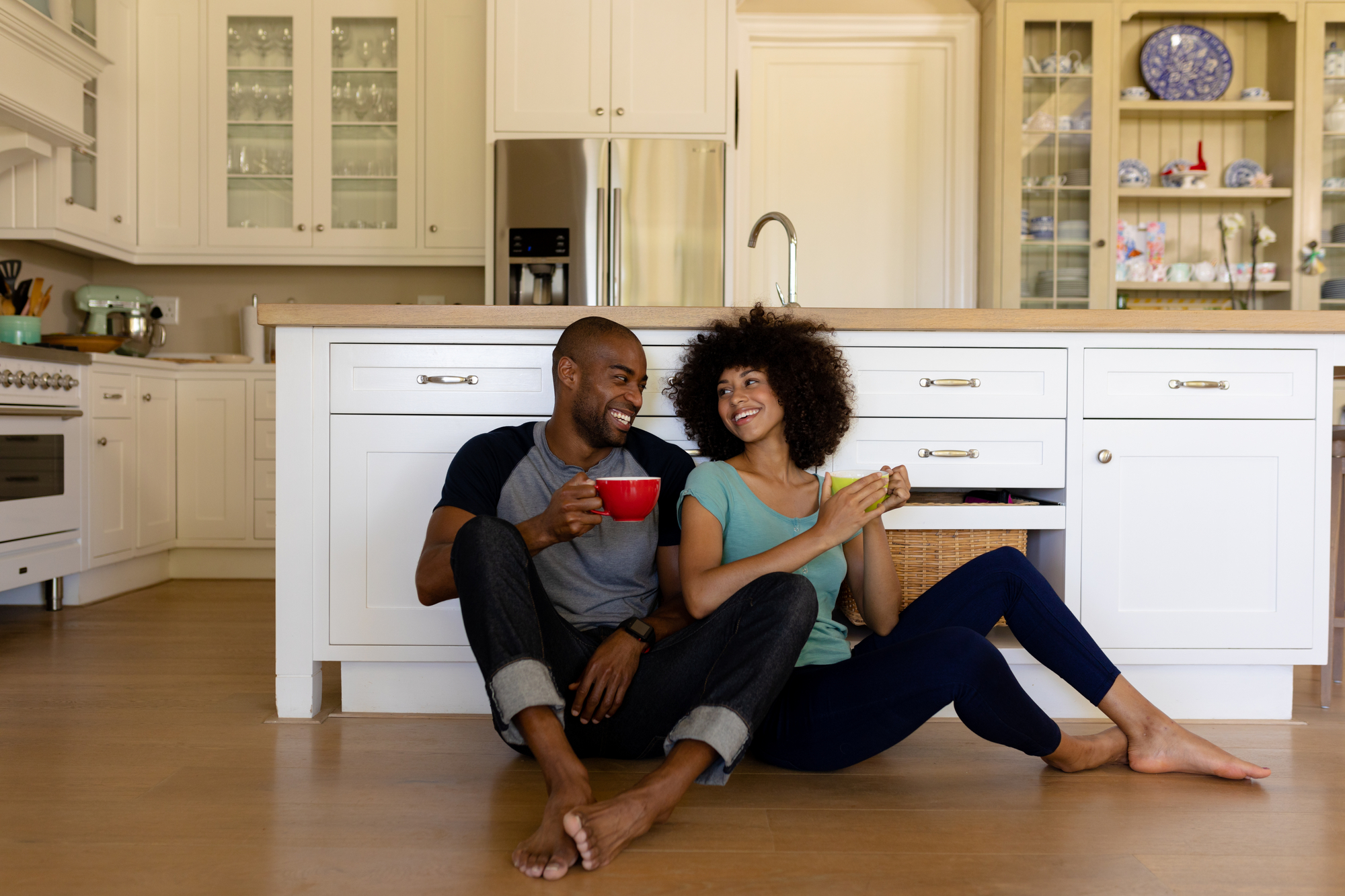 Happy couple sitting on the floor of their new kitchen.