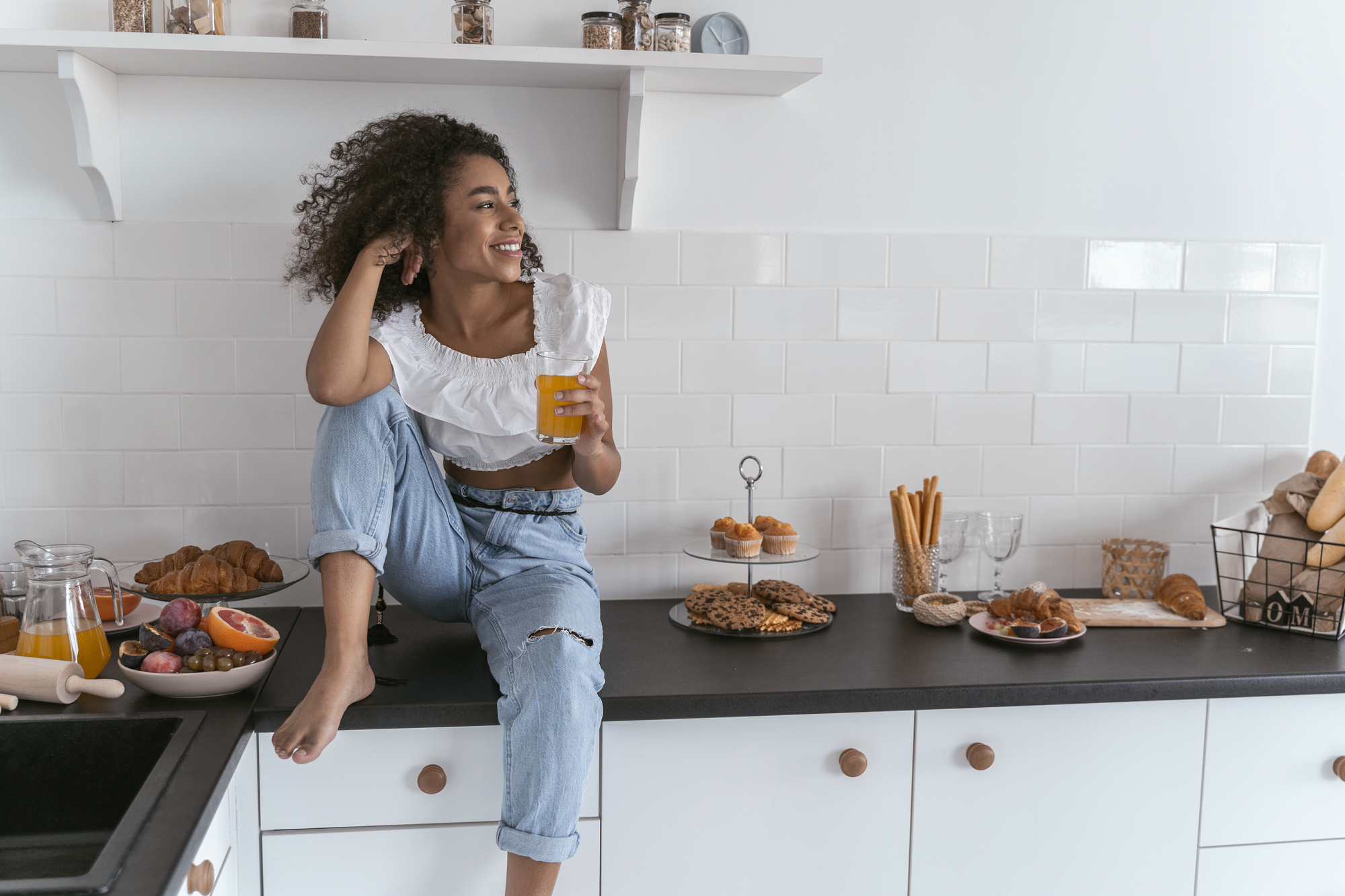 Woman stting on her kitchen countertop smiling.